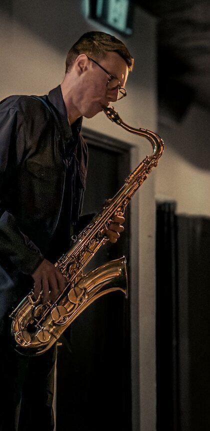 Saxophonist performing indoors in warm evening light